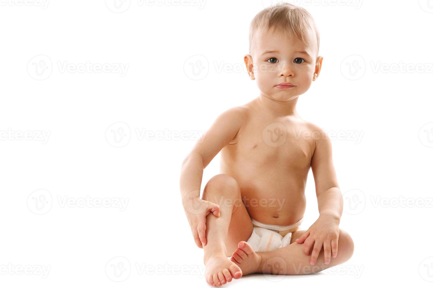 Curious healthy little boy in diaper sitting and looking. photo