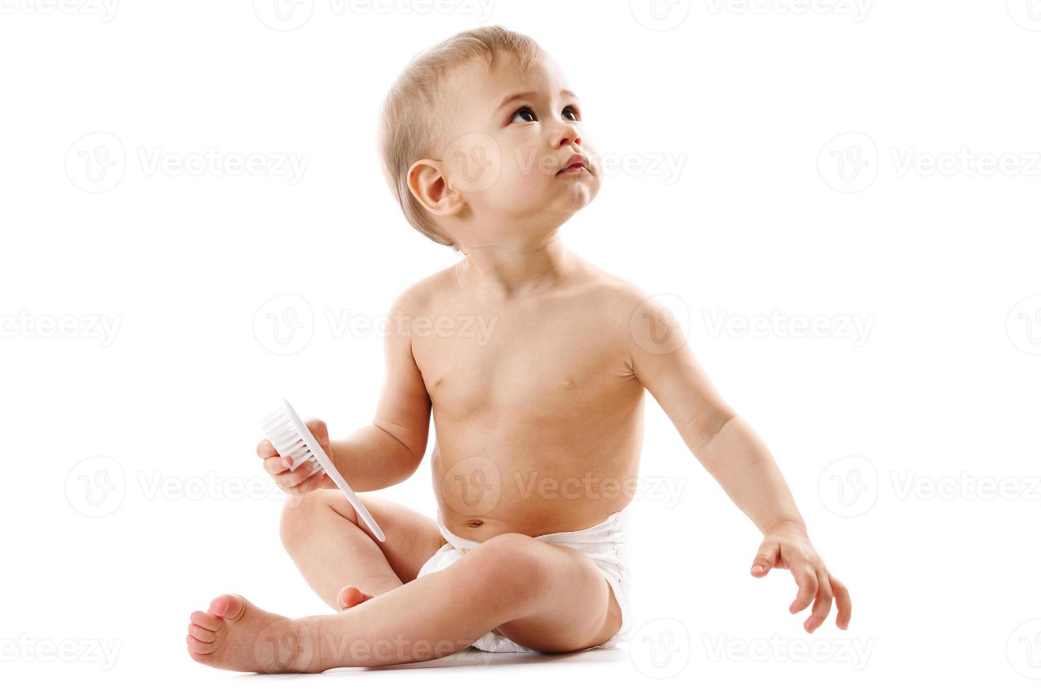 Little boy in diaper sitting and playing with brush. photo