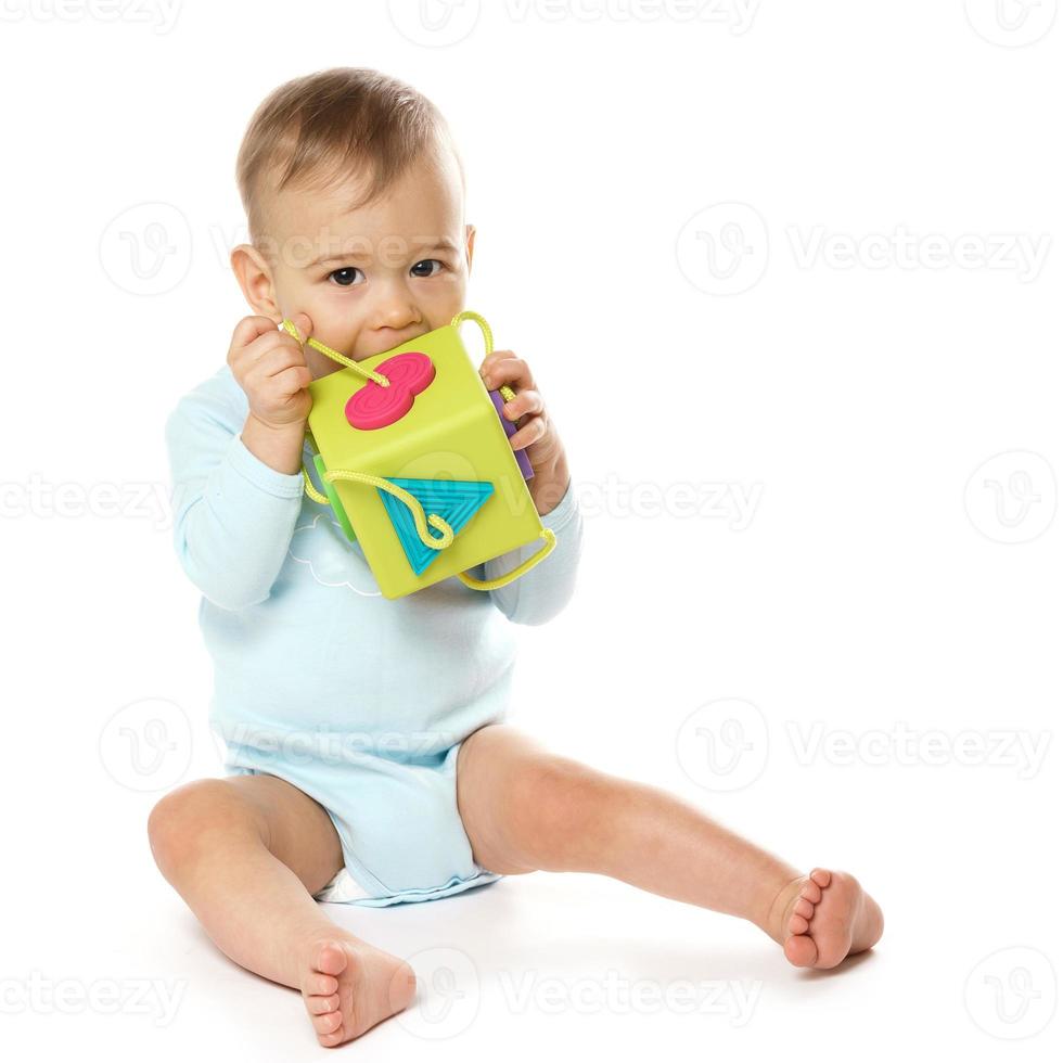 Little boy in romper sitting and playing with plastic toy. photo