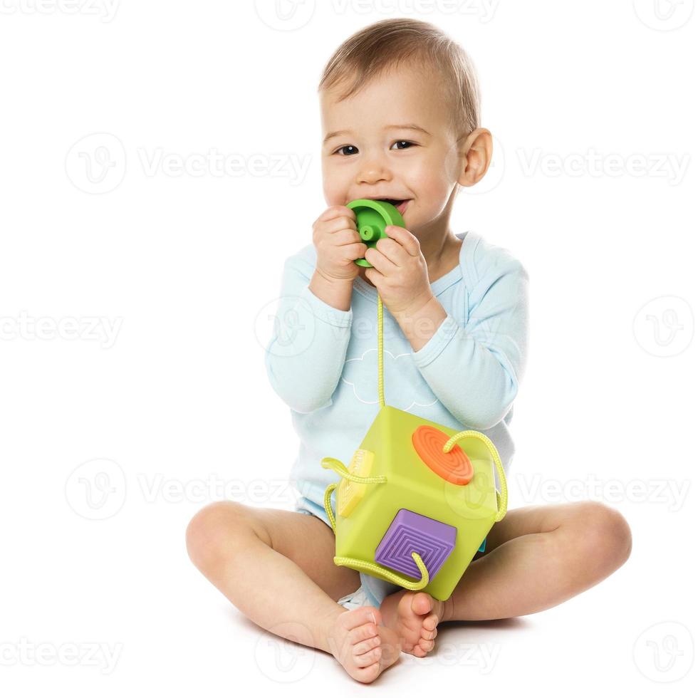 Little boy in romper sitting and playing with plastic toy. photo