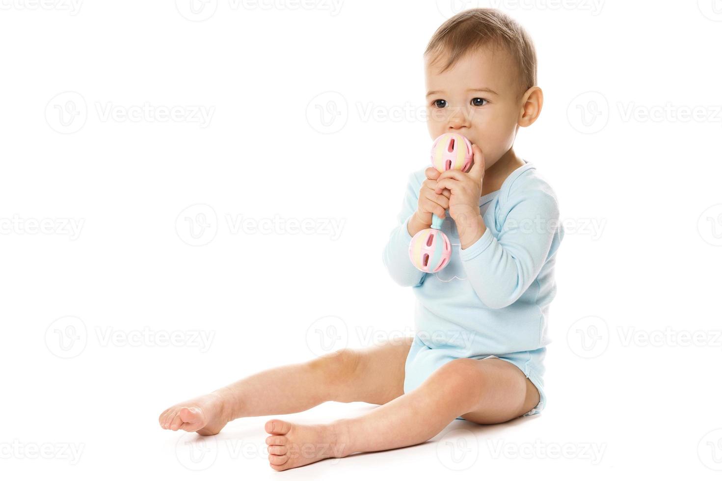 Little boy in romper sitting and playing with plastic rattle. photo