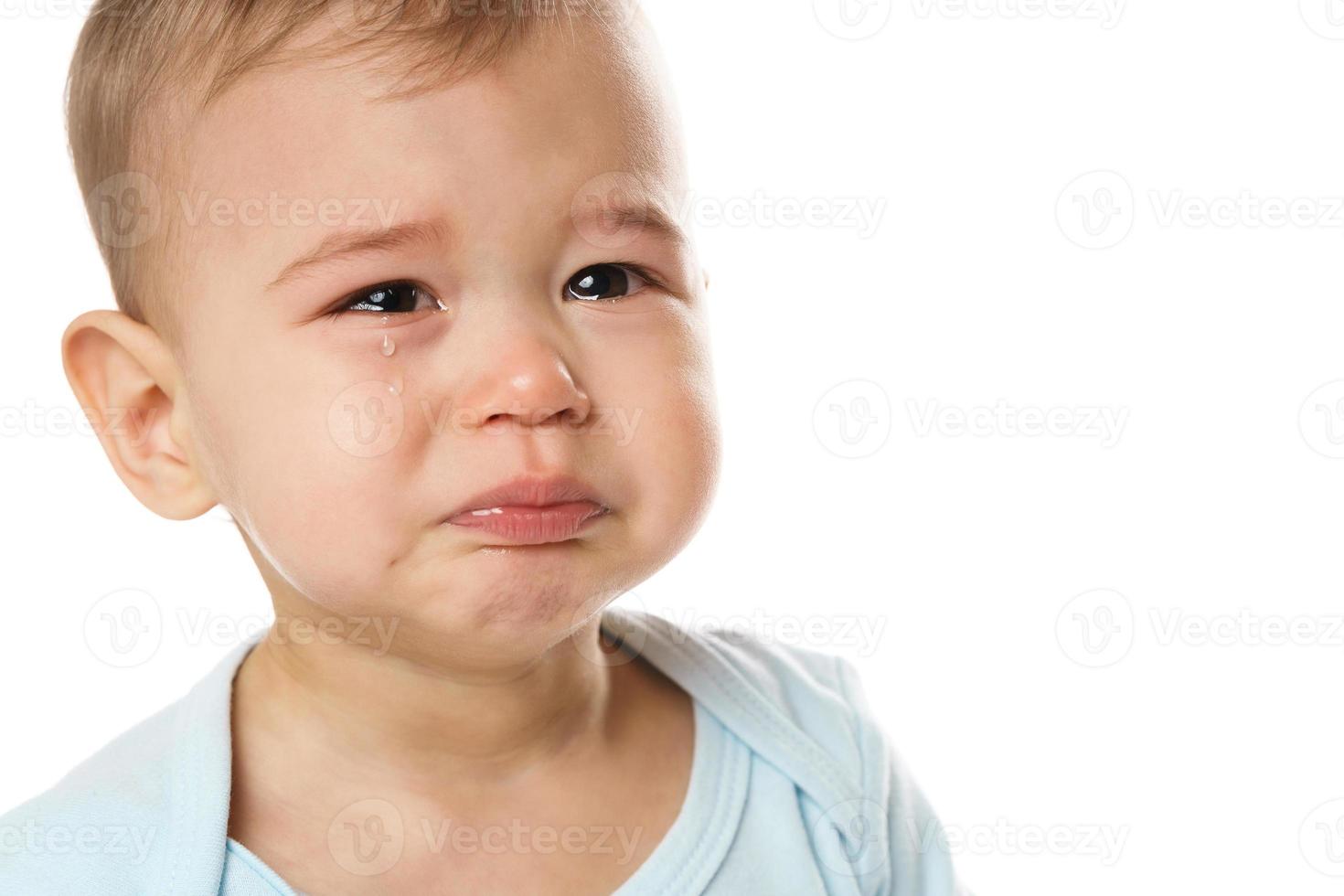 Closeuo shot of face of crying little boy in romper. photo