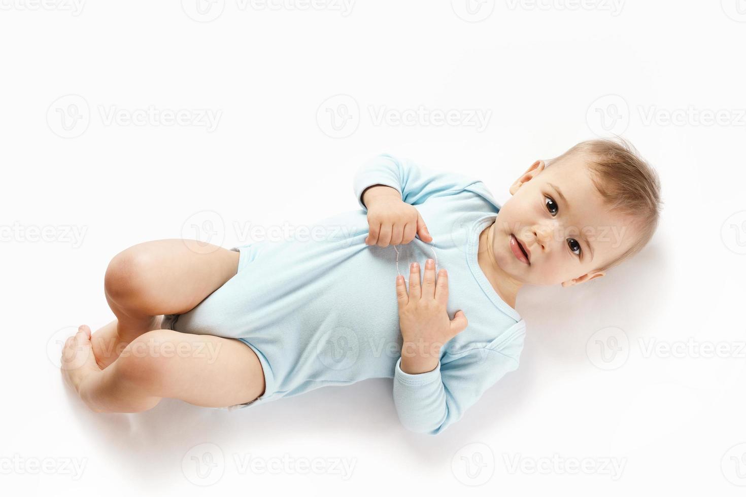 Little boy in romper lying on back and looking. photo