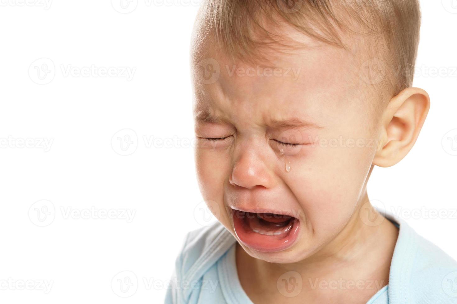 Closeuo shot of face of crying little boy in romper. photo