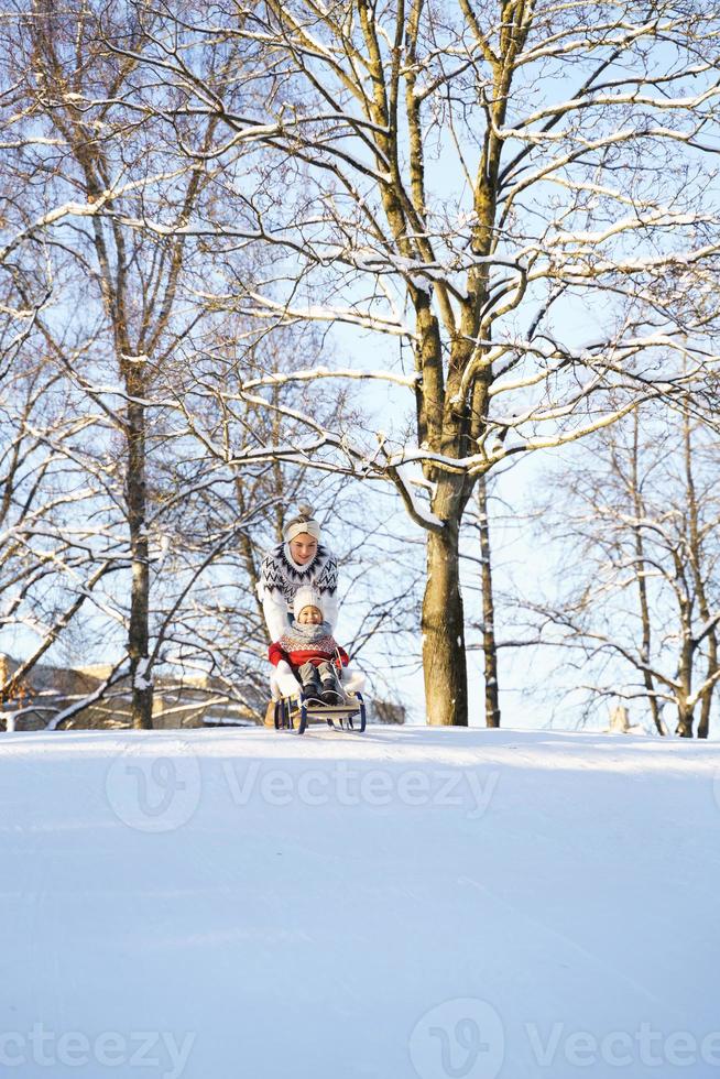 Mother and her cute little son having on a sledding hill photo