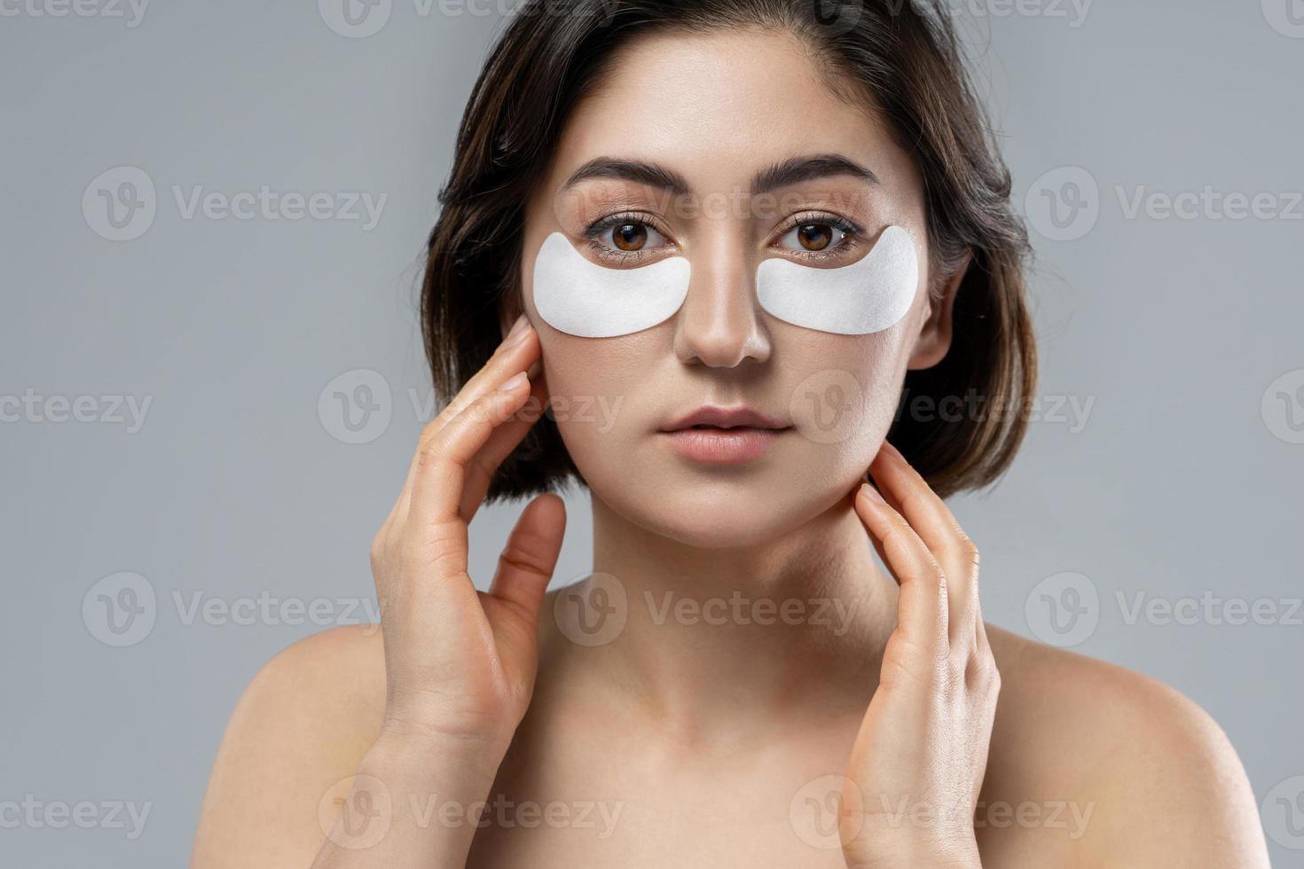 Beautiful woman with a smooth skin applying adhesive undereyes patches
