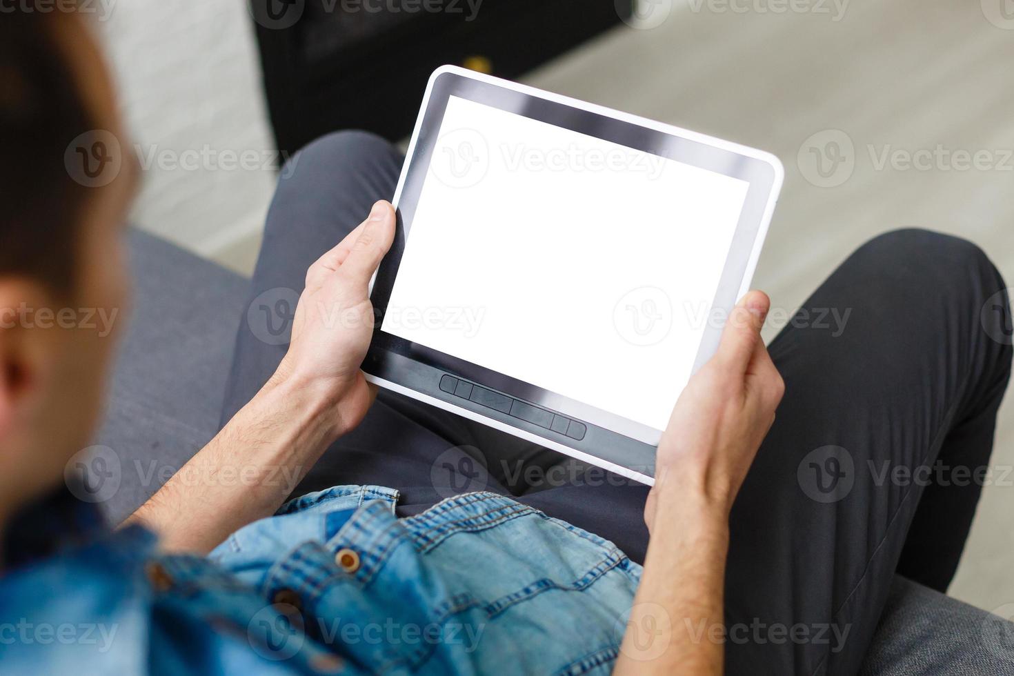 Man using tablet computer while sitting on a wooden floor. View from above. Clipping path included photo