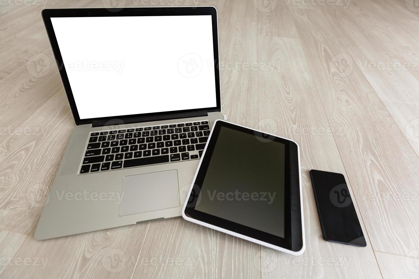 Modern laptop, mobile phone, tablet, and notebook on white wooden background photo