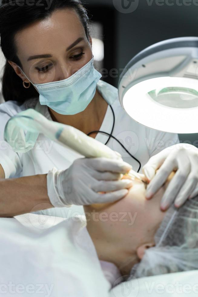 Permanent makeup artist and her client during lash line enhancement treatment photo