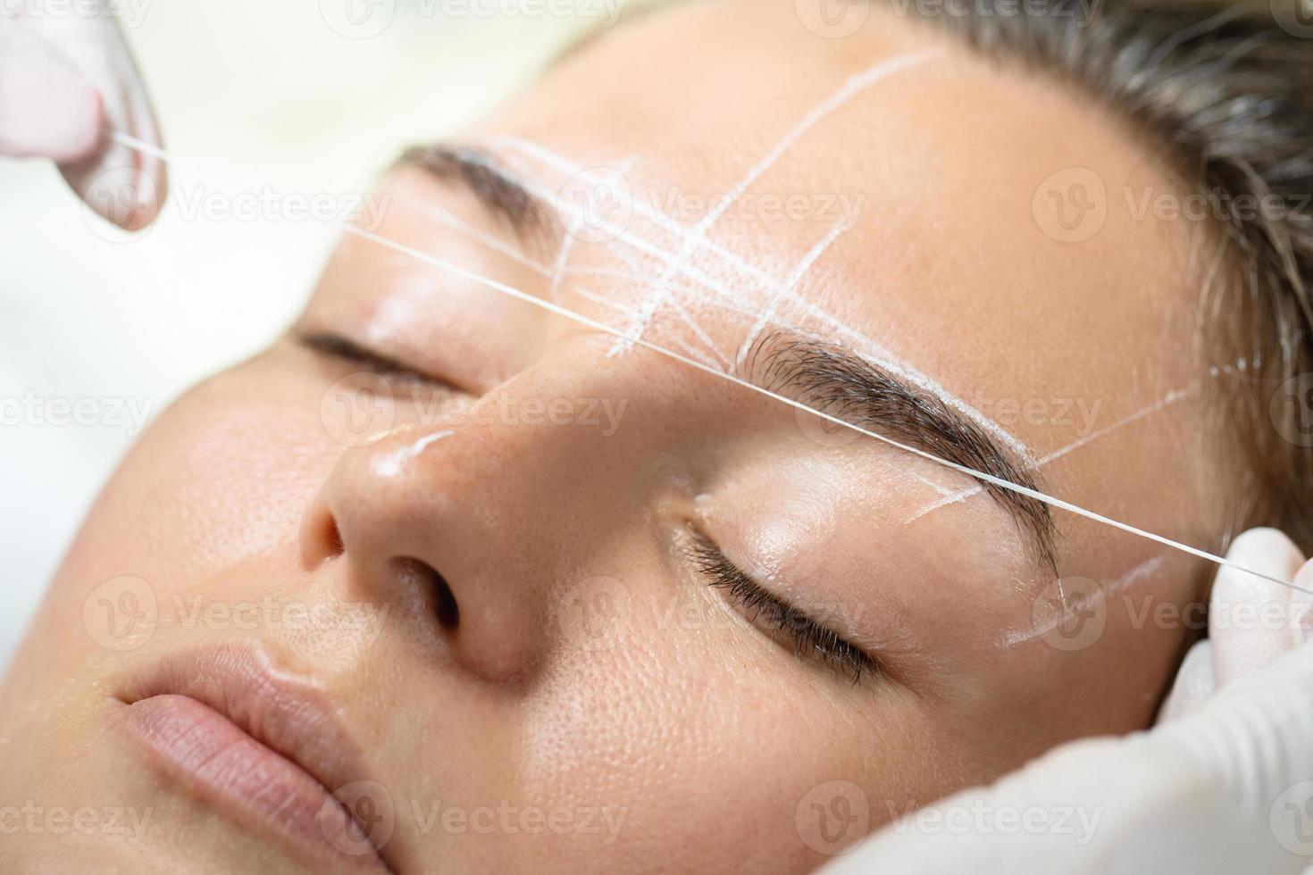 Woman during professional eyebrow mapping procedure photo