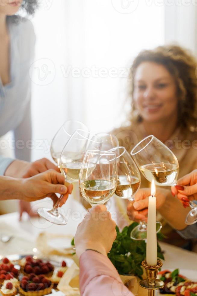 jóvenes amigas tintineando vasos en la mesa festiva. foto