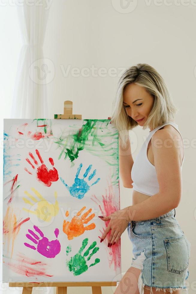 Young woman drawing with her palms using colorful rainbow colors to support LGBT community photo