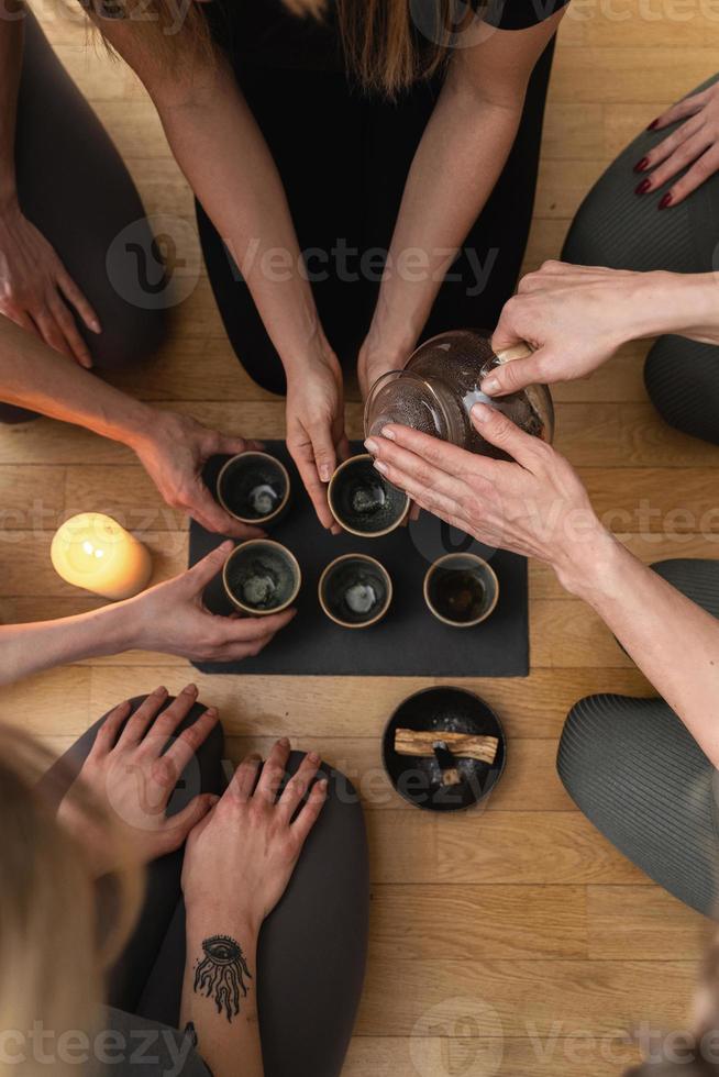 Woman pouring tea to her friends during tea ceremony. photo