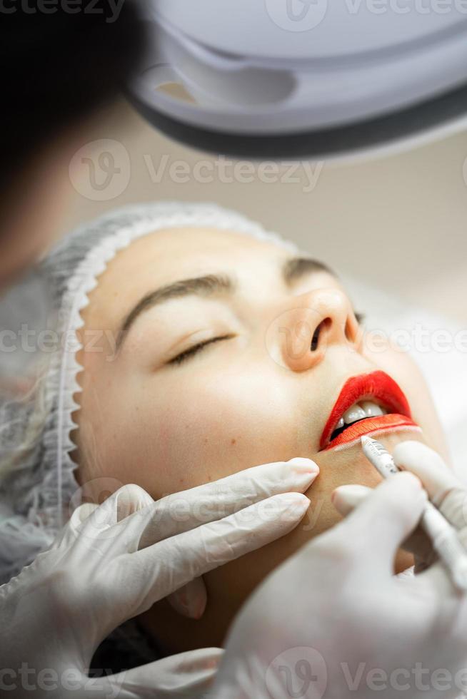 Permanent makeup artist and her client during lip blushing procedure photo