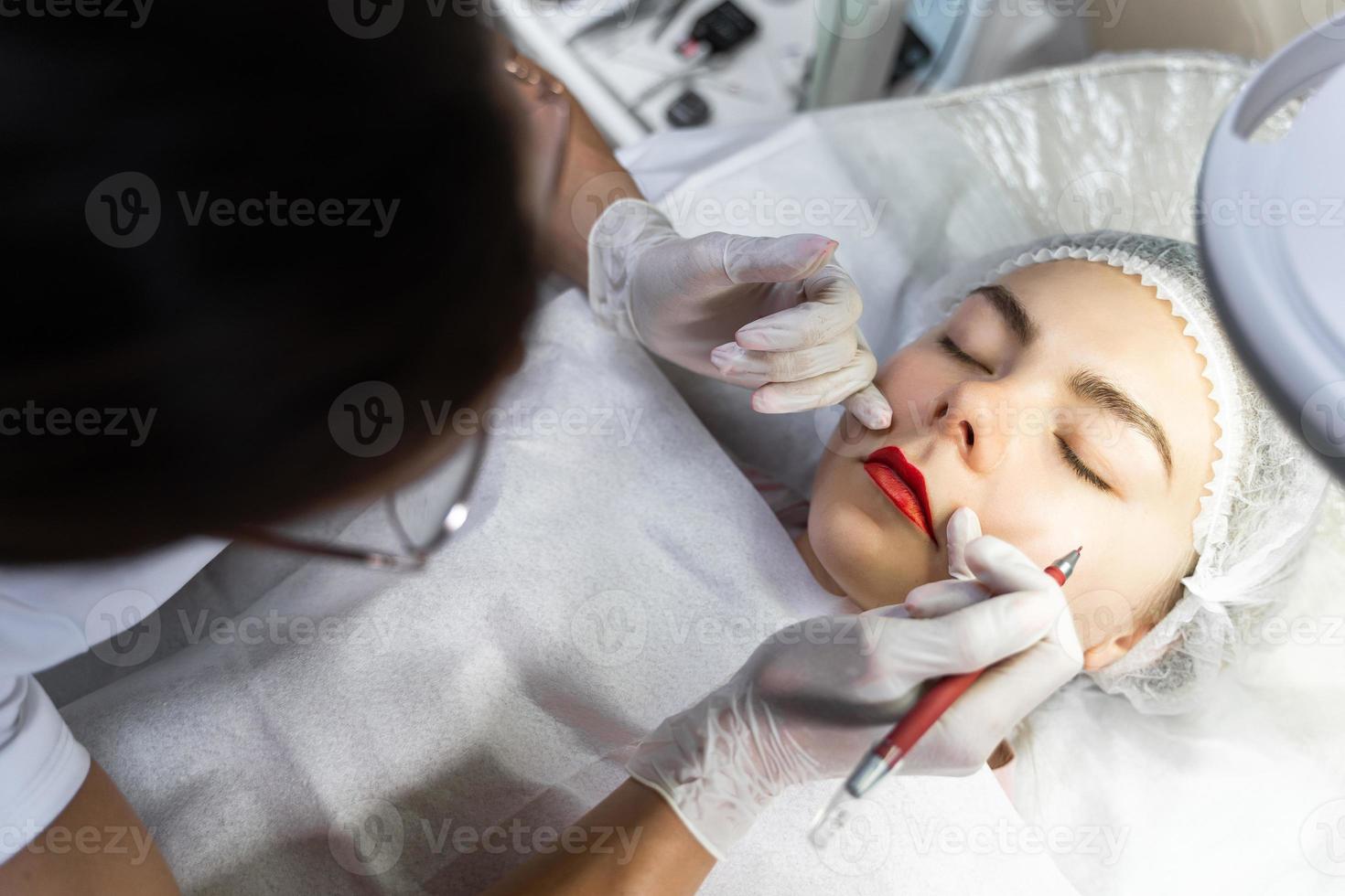 Permanent makeup artist and her client during lip blushing procedure photo