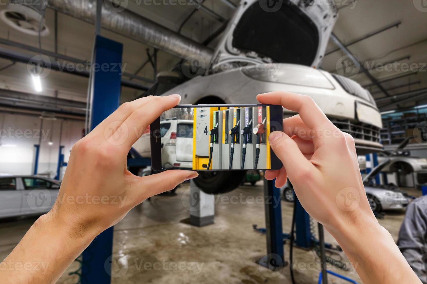 Closeup of man with broken car and smart phone, Man hand holding mobile smart phone , tablet,cellphone over Blurred of car technician repairing the car in garage background. photo