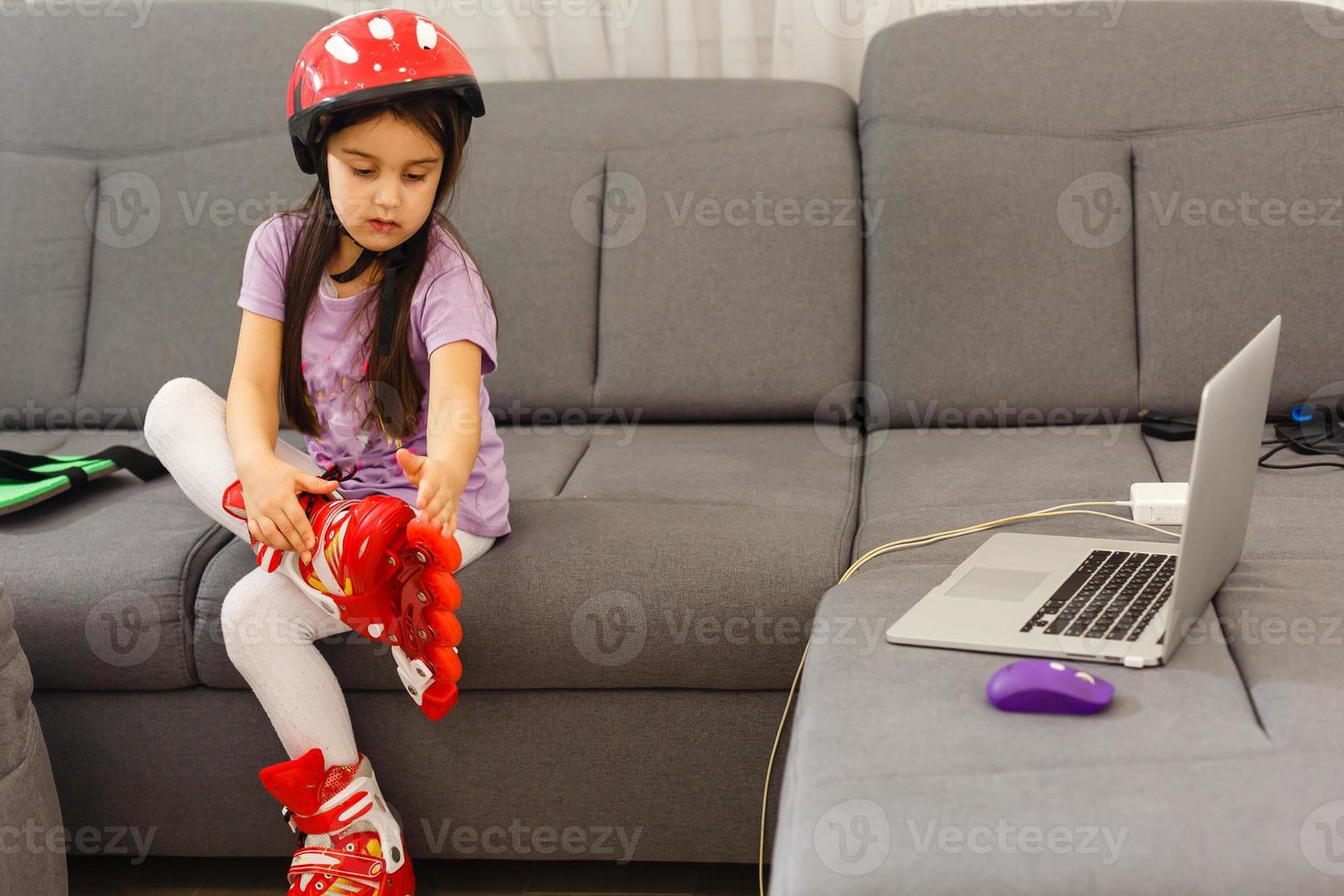 Little girl preschool sitting wearing her roller skates and crossing her legs photo