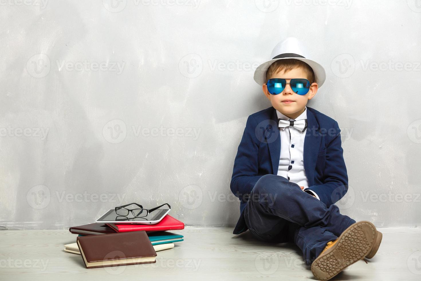 Elementary school student carrying notebooks over a gray background photo