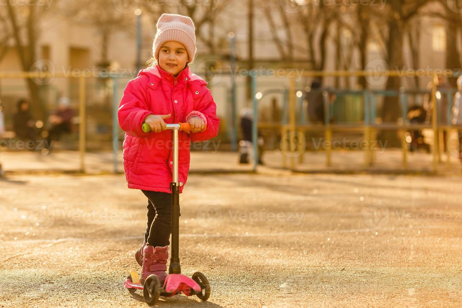 Little girl riding a kick-scooter photo