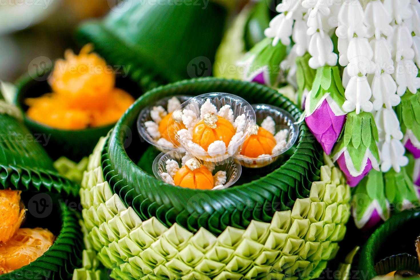 Closeup and crop banana leaves folded in a bowl and pot shape with ancient Thai desserts on blurred background. Thai desserts are unique in Thai national culture. photo