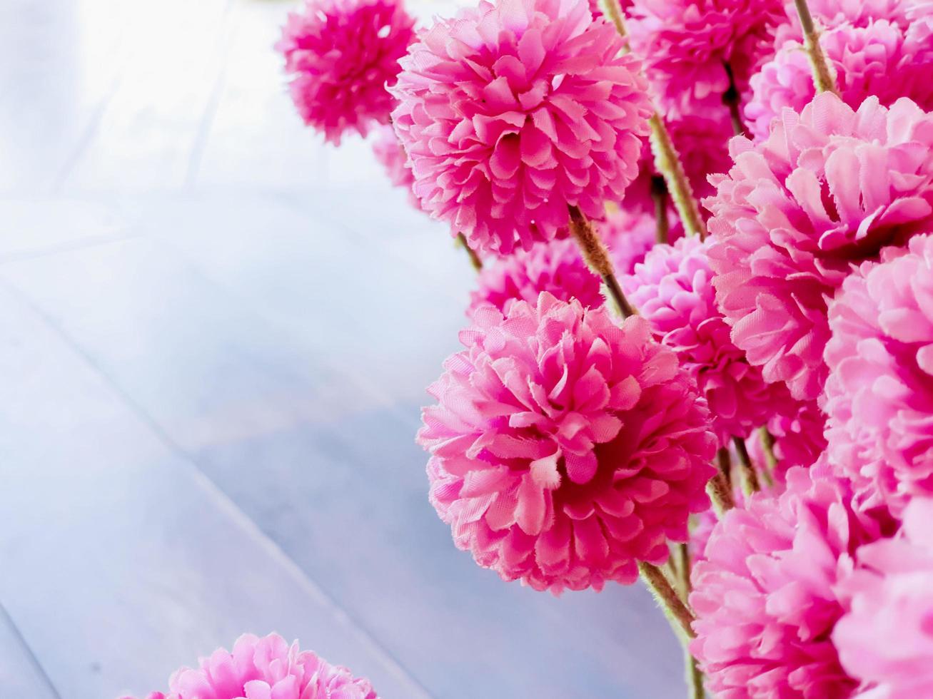 Closeup fabric pink flowers with natural sun light and wooden floor background. photo