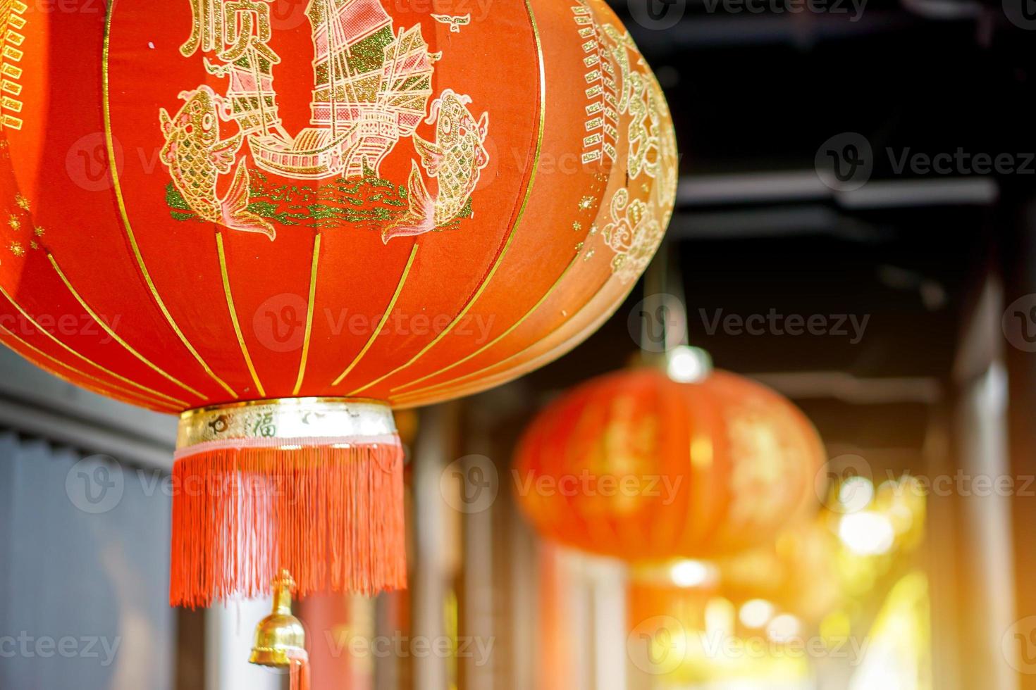 Closeup and crop Chinese red lanterns hang on ancient shrine ceiling with blurry and sun flare background. Chinese letters on lantern is mean fortune blessing compliment in English. photo