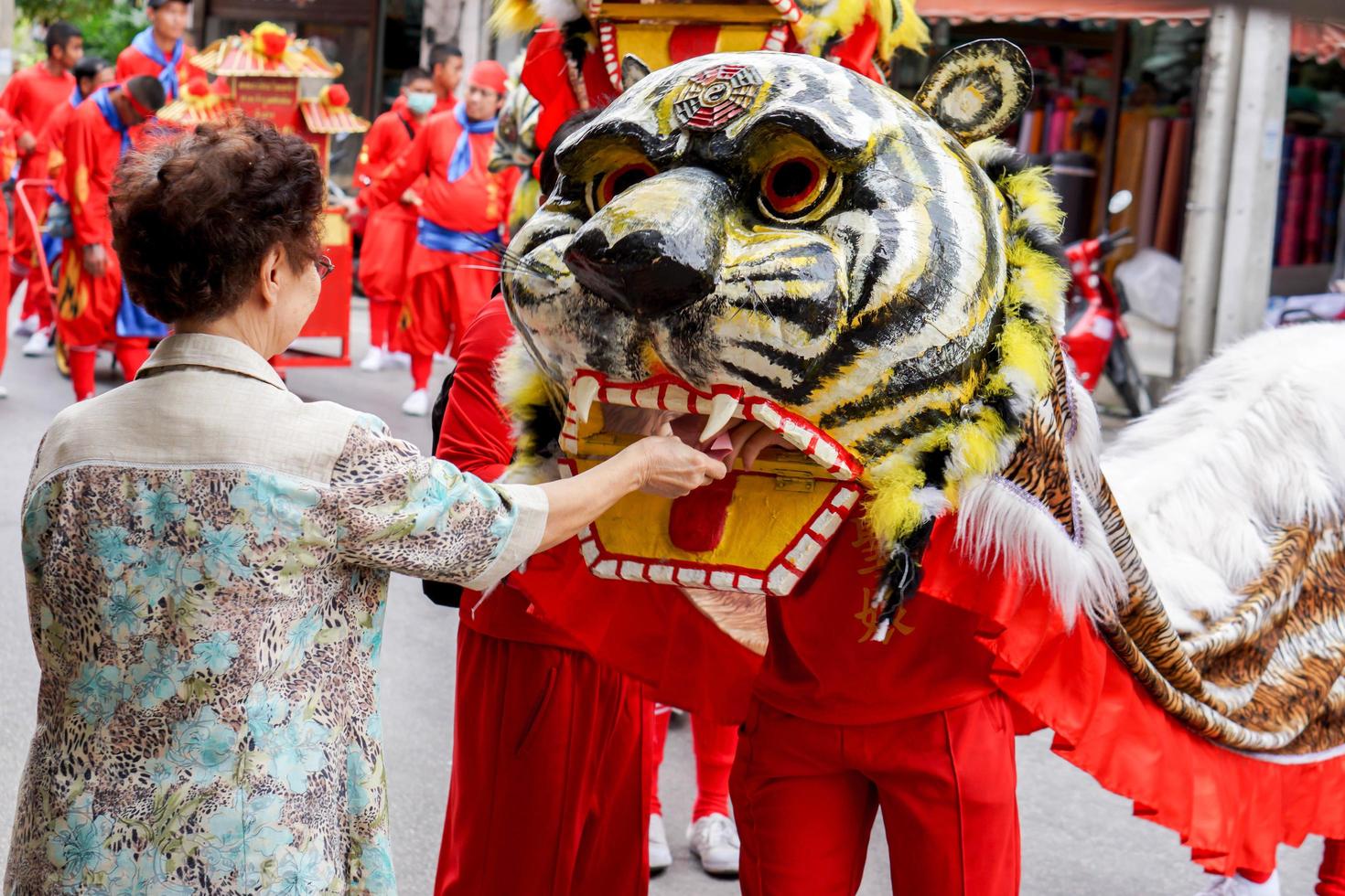 12 December 2018 Chinese woman give a reward money to Chinese tiger dancer and performance theater group for show in Chinese respect the gods celebration of Lampang city. photo