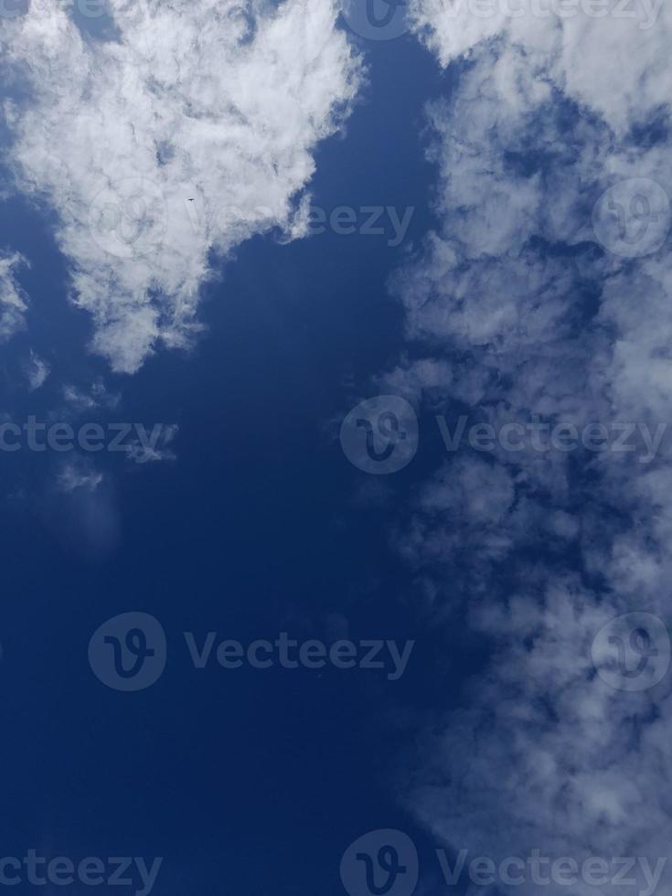 White clouds in the blue sky. Heaven and infinity. Beautiful bright blue background. Light cloudy, good weather. Curly clouds on a sunny day. photo