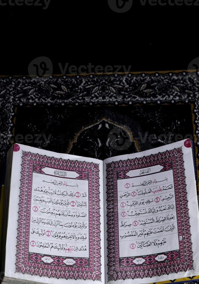 Al-Quran which is above the prayer rug with a black background photo