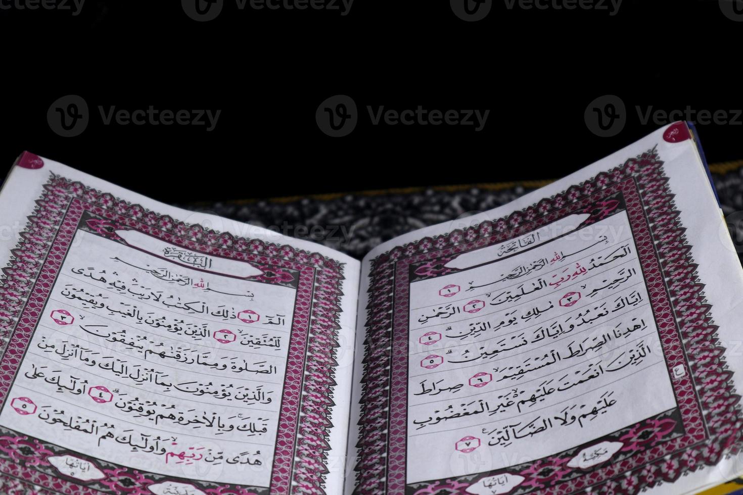 Al-Quran which is above the prayer rug with a black background photo