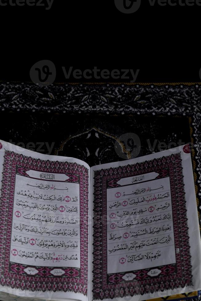 Al-Quran which is above the prayer rug with a black background photo