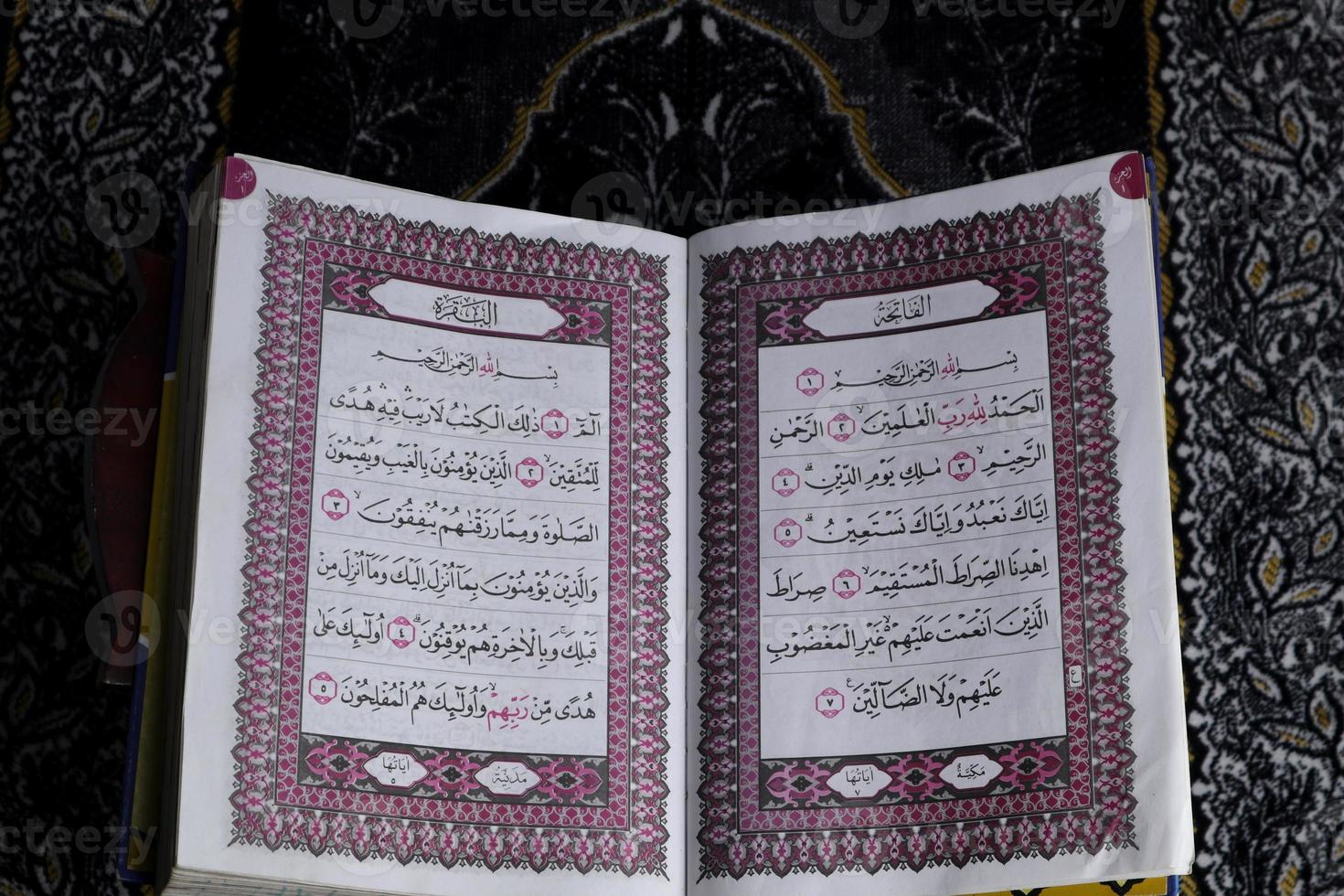 Al-Quran which is above the prayer rug with a black background photo