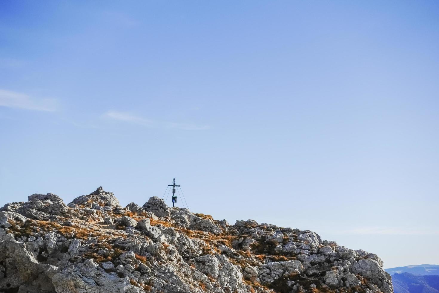 little summit cross on a rocky mountain with sky photo