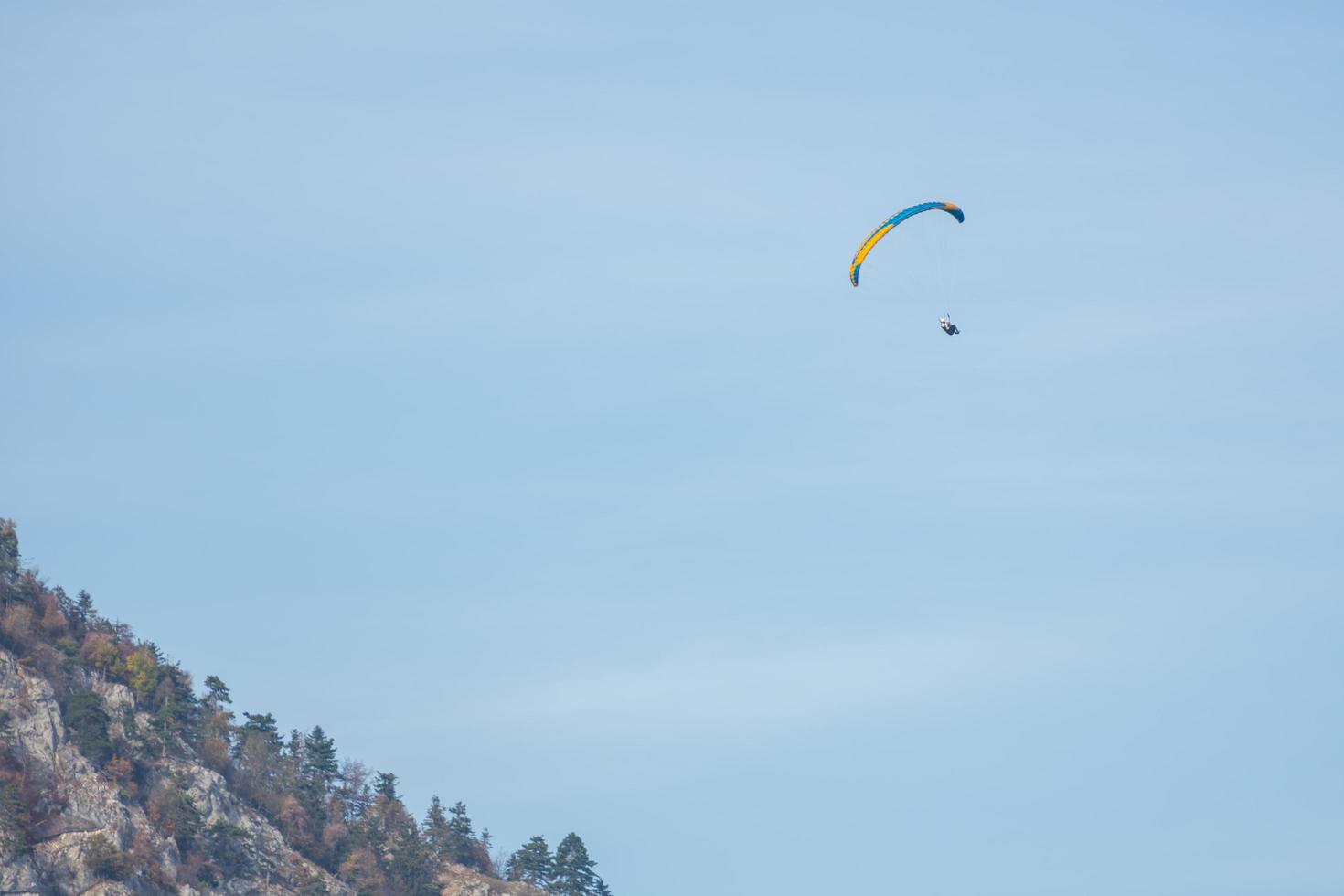 single paraglider on blue sky near a high mountain photo