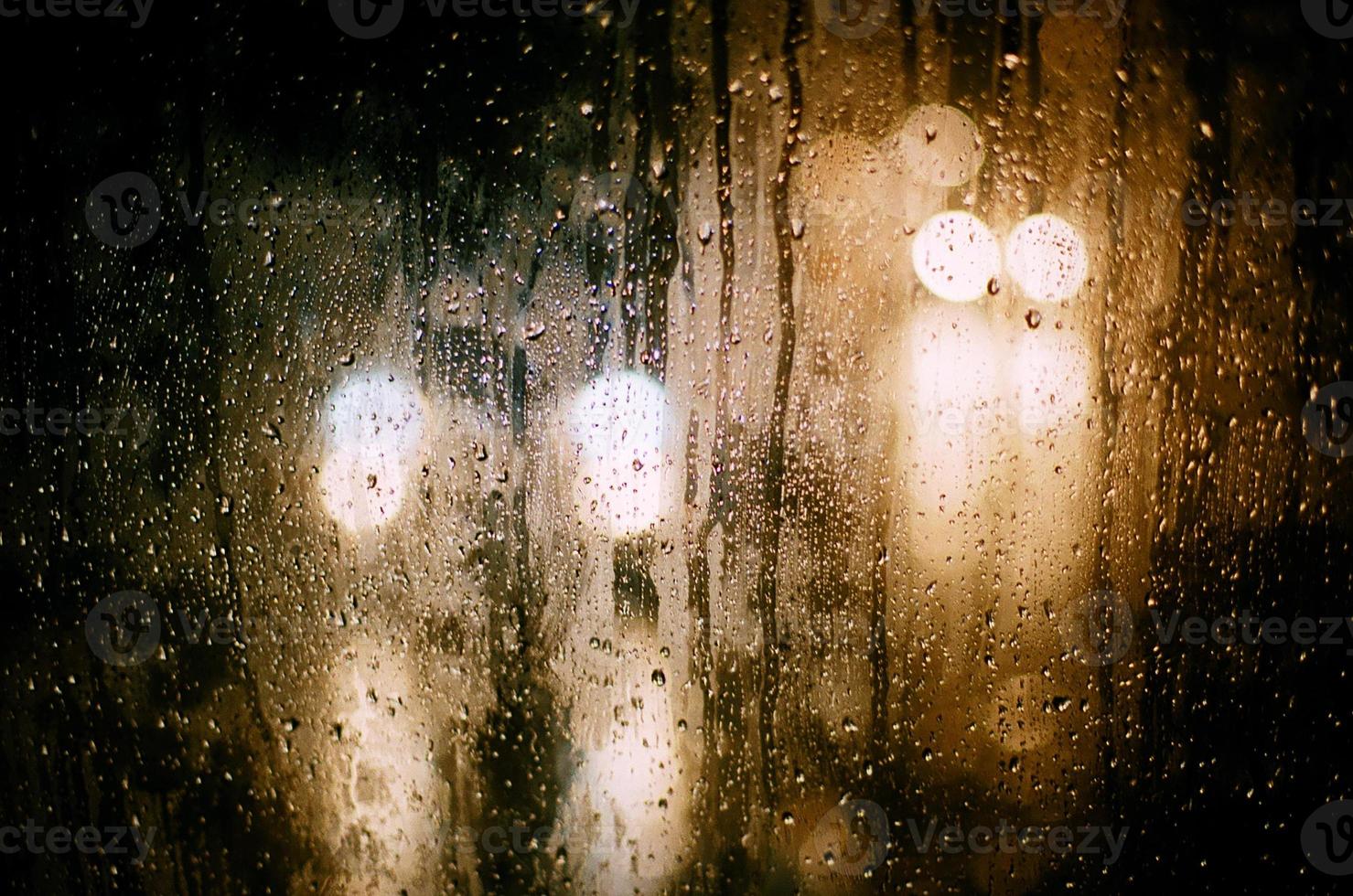 on the glass round reflections of the blurred light of car headlights during the rain. photo