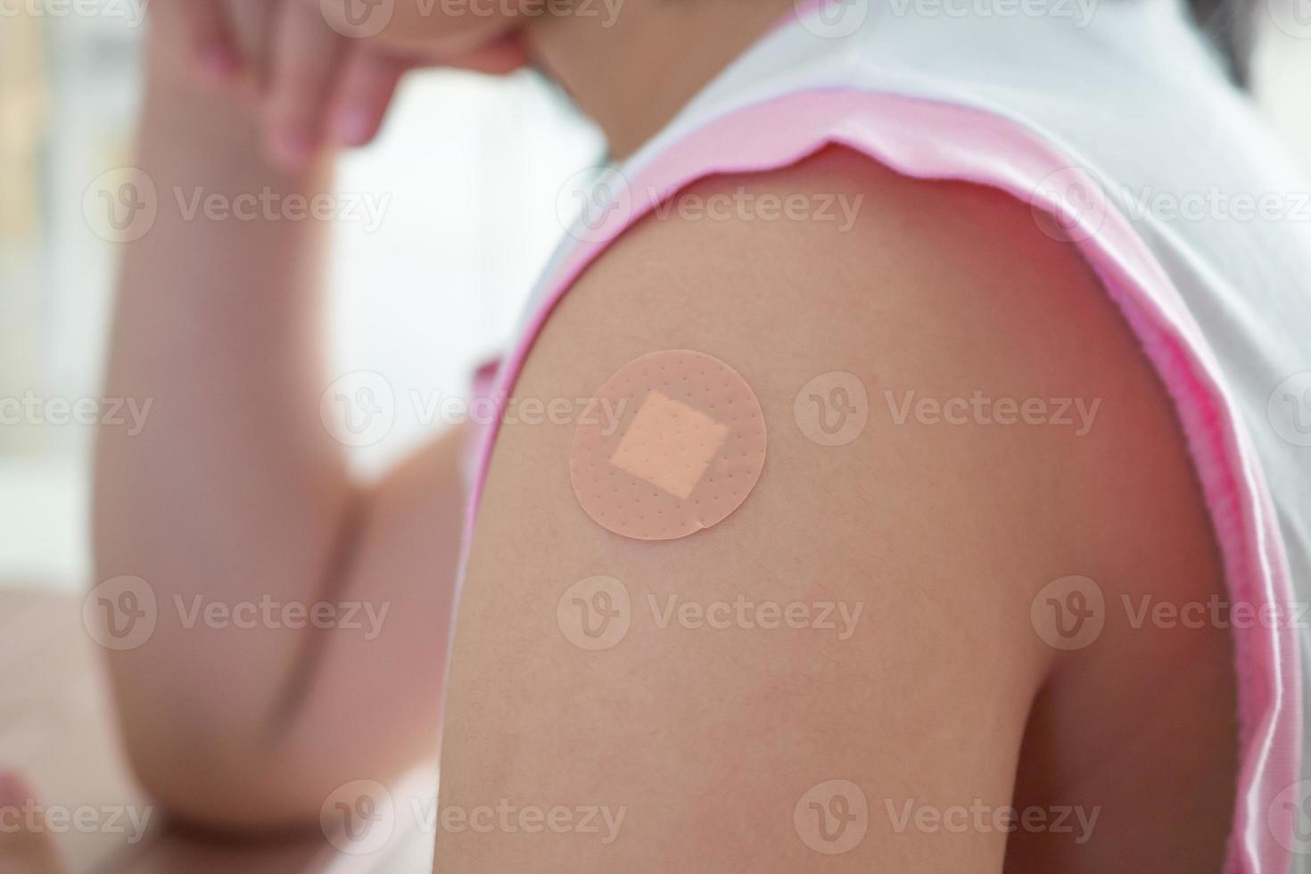 Vaccinated little asian girl with adhesive plaster after vaccine injection photo