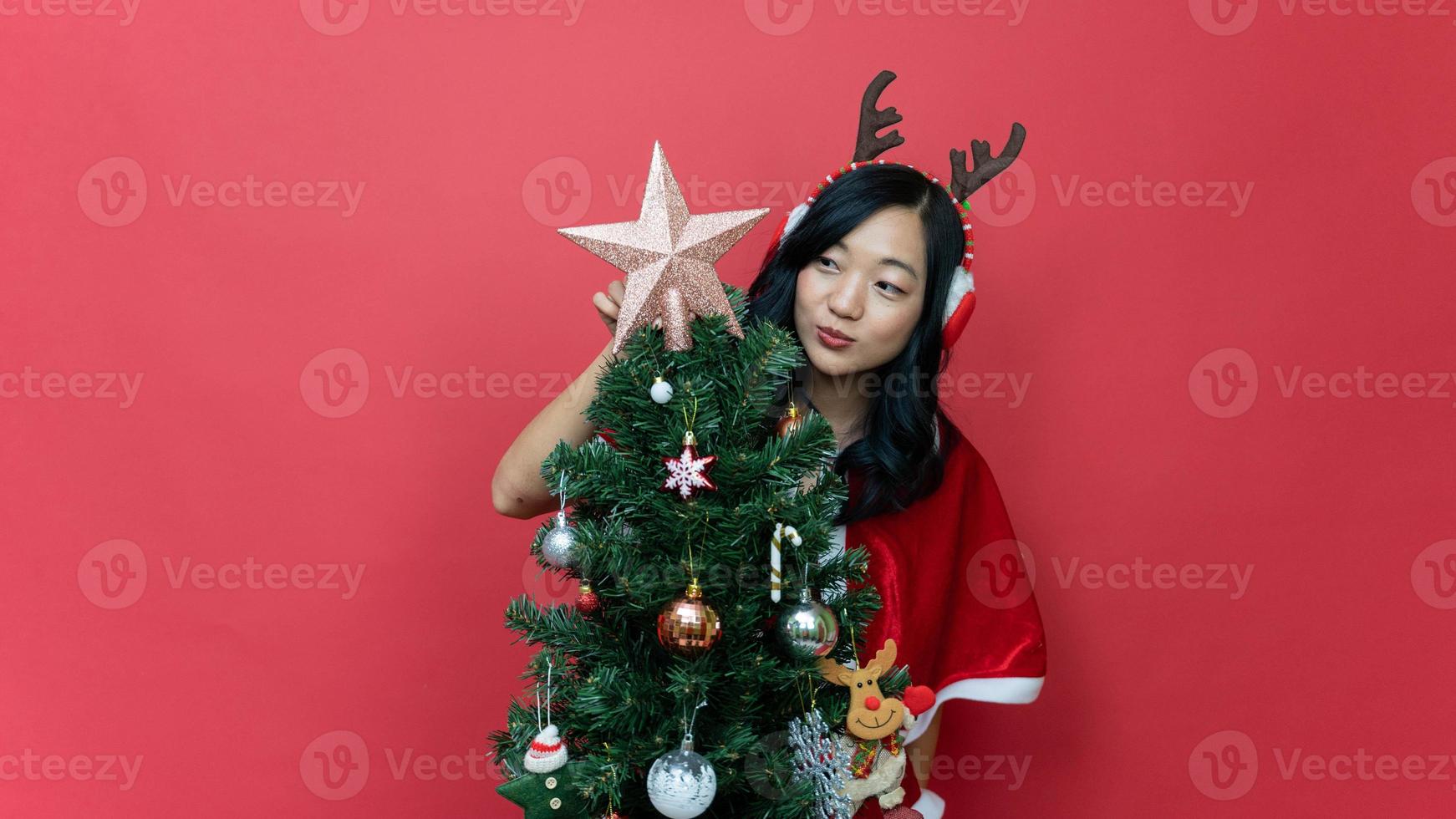 Beautiful young asia woman in red santy costume decorate the Christmas tree. New Year celebration. Christmas eve. photo