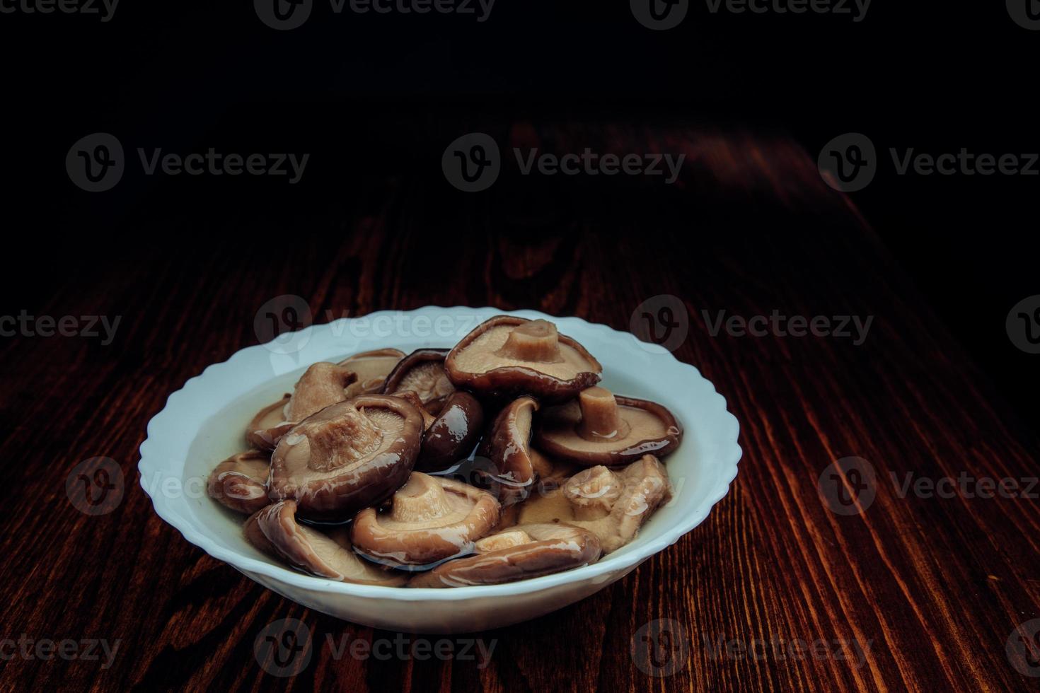 A white plate of pickled mushrooms . Healthy village food . Pickled black milk mushroom . photo