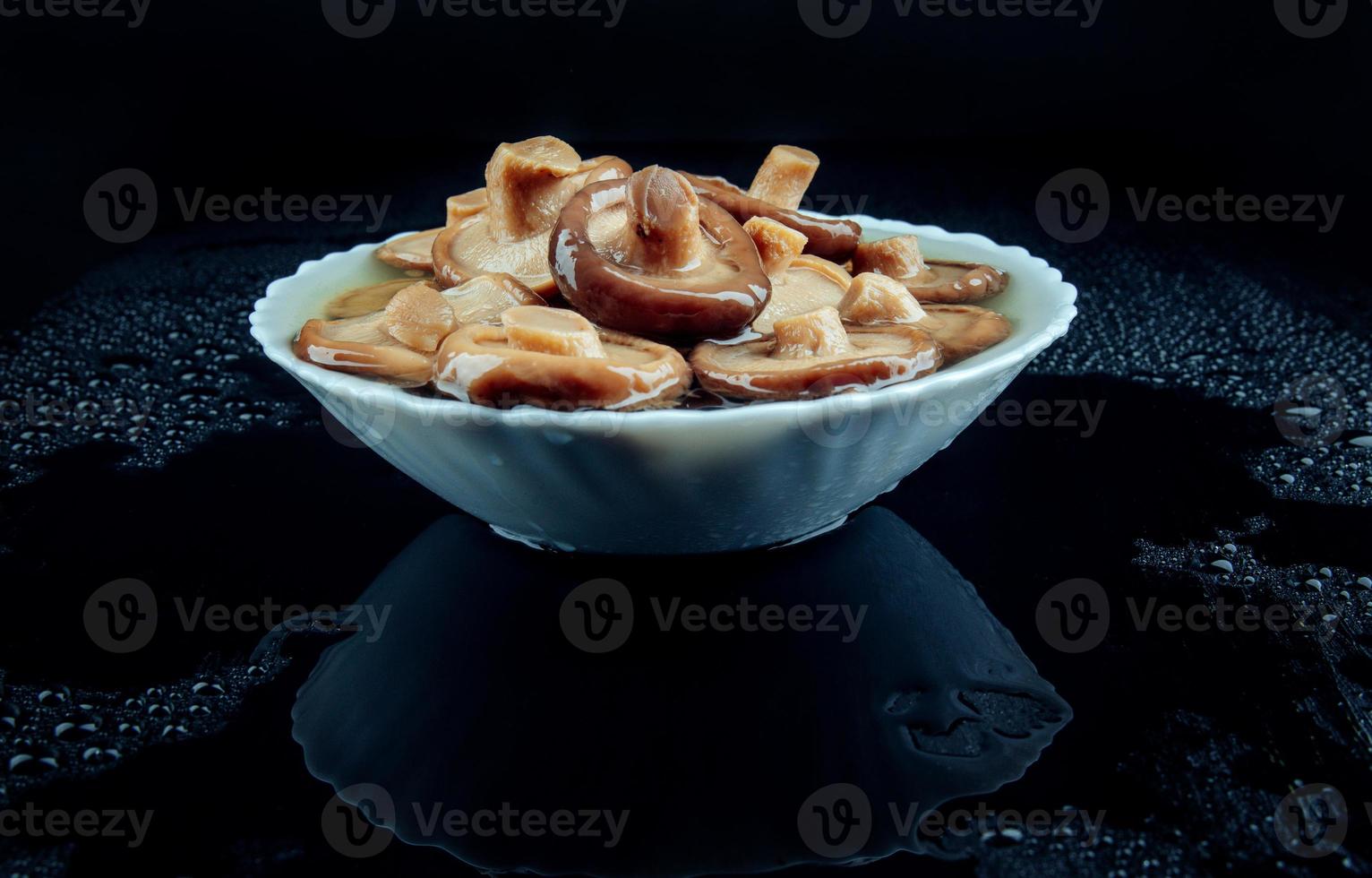 Salted mushrooms in a plate on a black background . Pickled black milk mushroom . photo