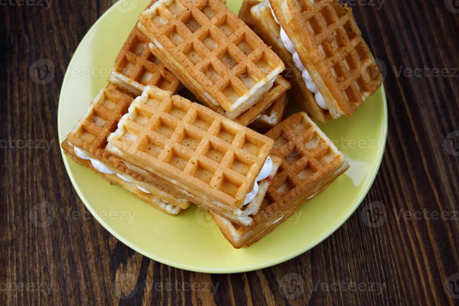 A pile of fresh Viennese waffles lie on a yellow plate. photo