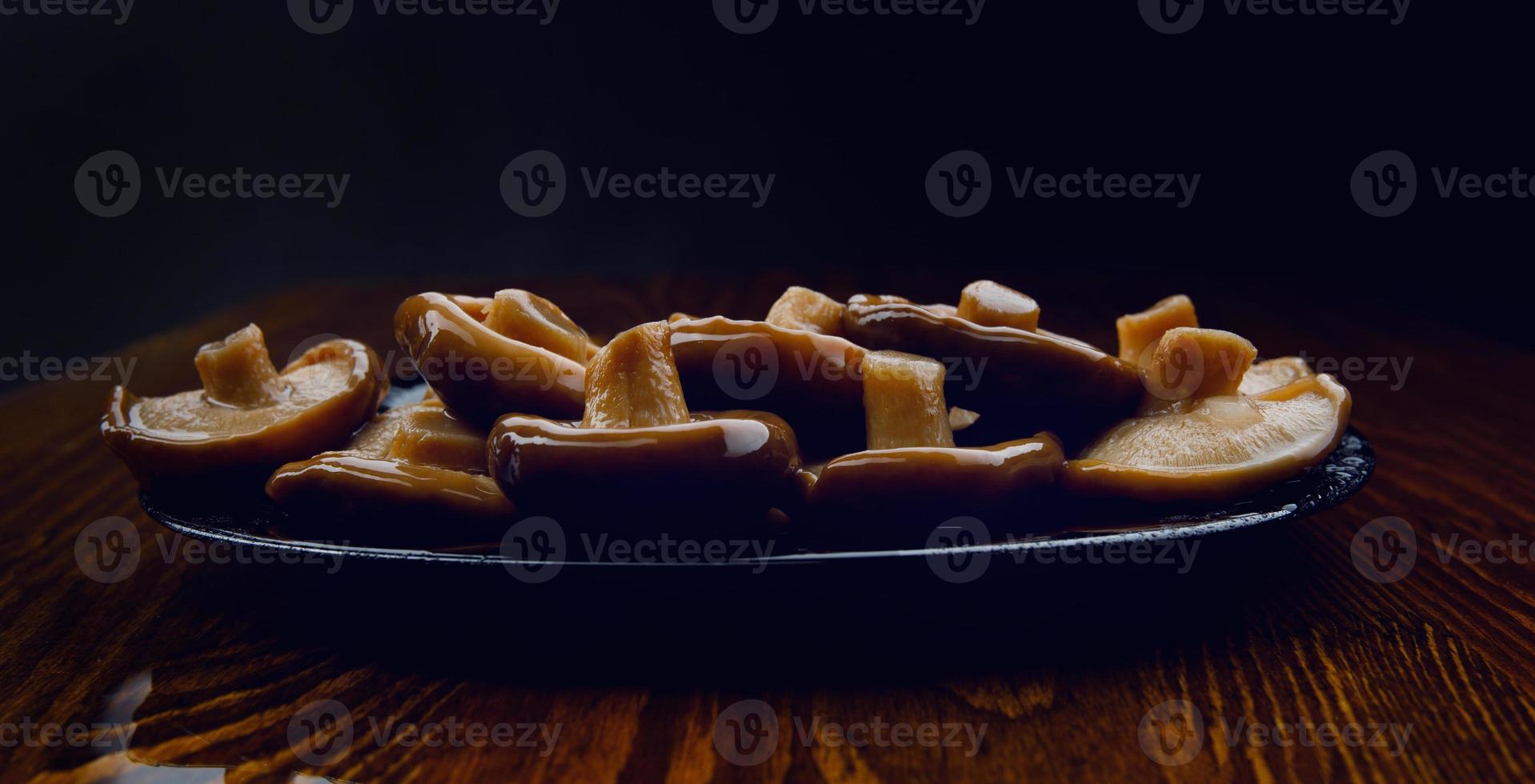 A scattering of pickled mushrooms in a black plate . Healthy village food . Pickled black milk mushroom . photo