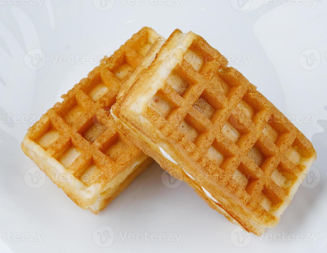 Delicious fresh Viennese waffles with white cream lie on a white plate. photo