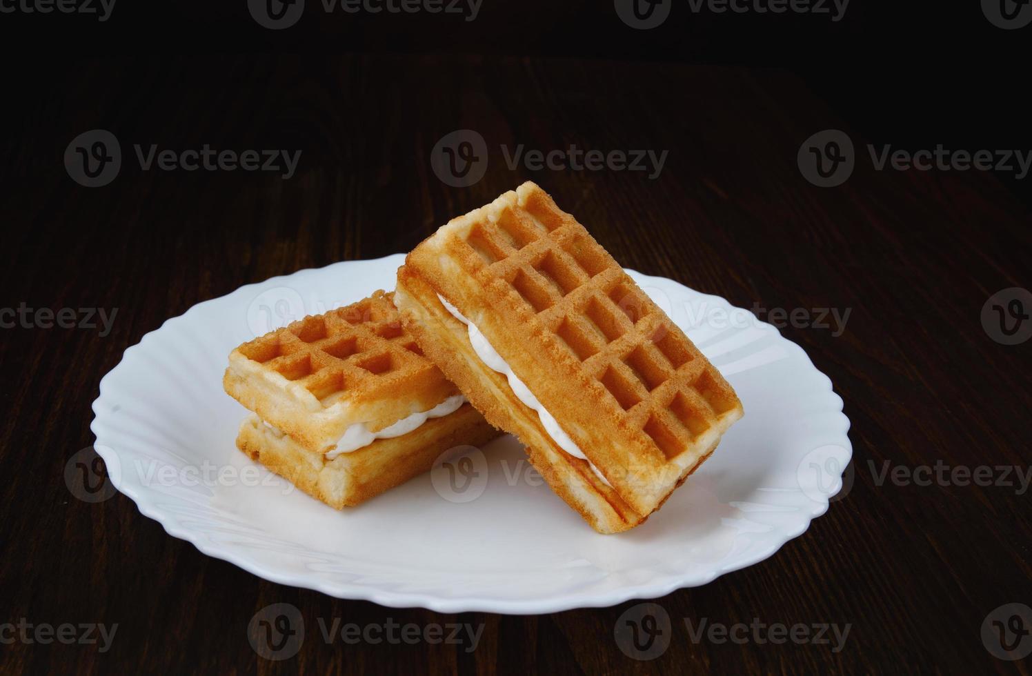 Fresh Viennese waffles with white cream on a white plate. photo