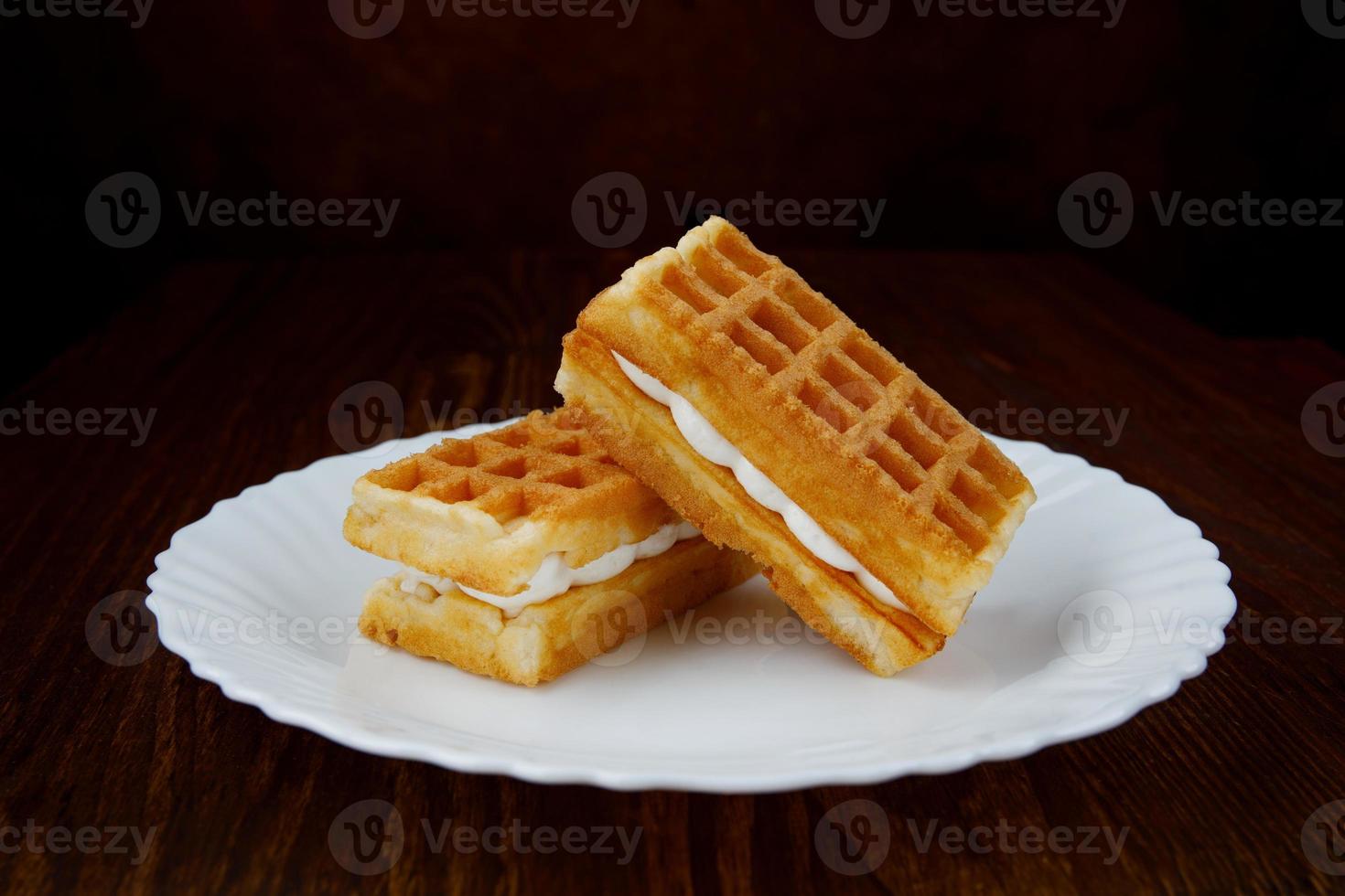 Delicious fresh Viennese waffles with white cream lie on a white plate. photo