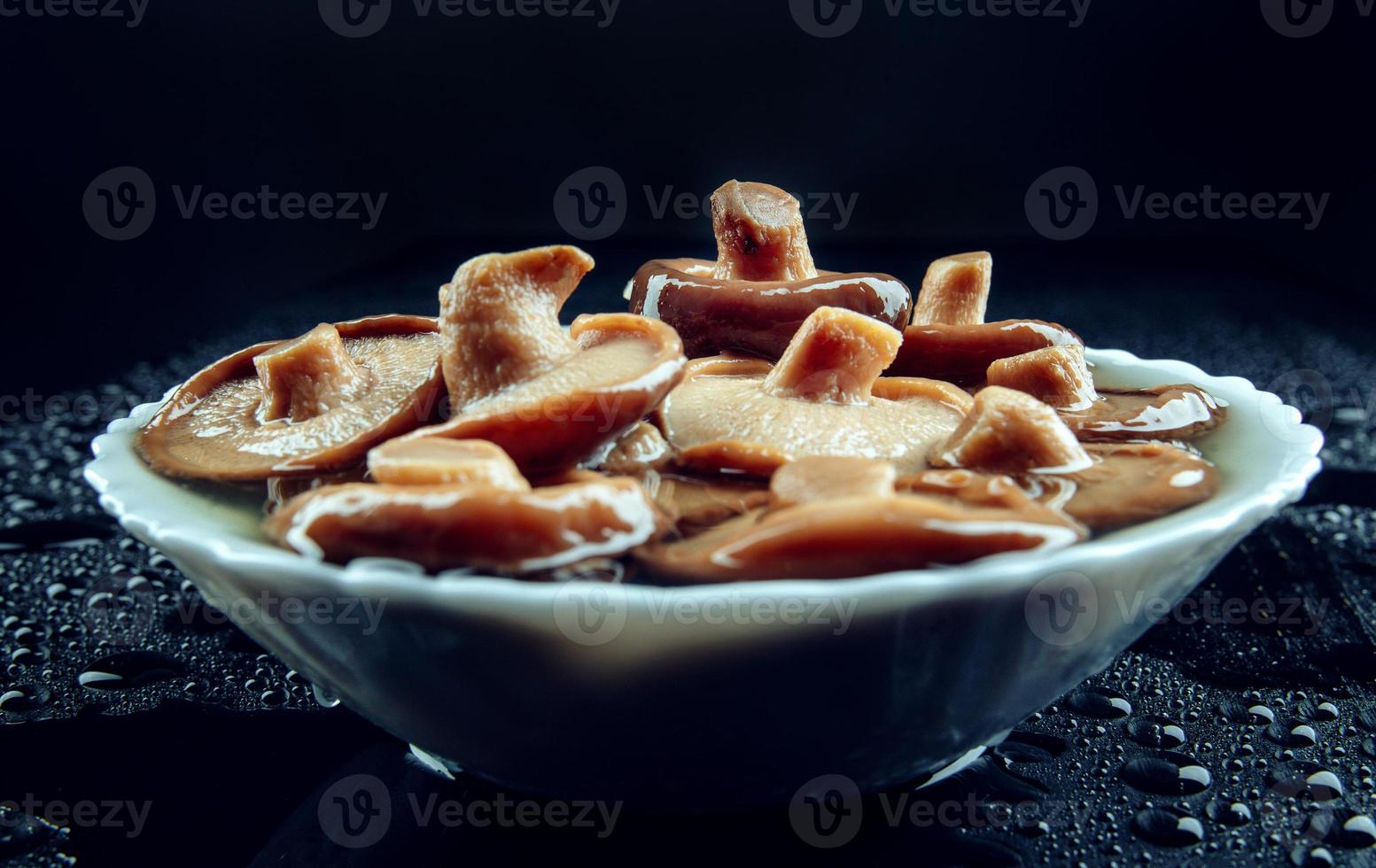 Salted mushrooms in a plate on a black background . Pickled black milk mushroom . side view . photo