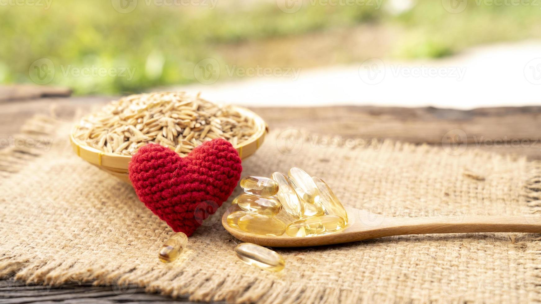 handicraft red heart with Capsule rice barn oil in wooden spoon with cold press rice barn oil. Rich in good fats, vitamin E, vitamin B helps prevent clogged fat in the arteries, healthy concept. photo