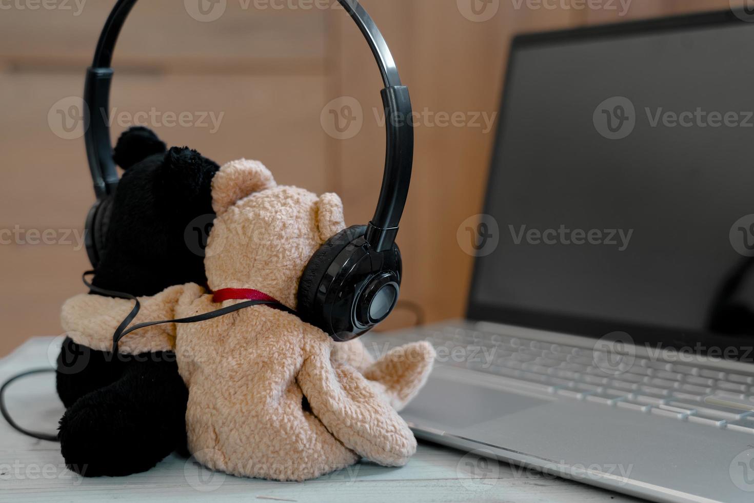 Two little bears wearing headphone listen music from laptop, relaxing time. photo