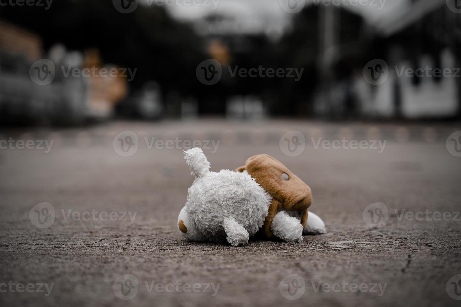 el oso de peluche solitario duerme en el piso de cemento para crear una postal de niños desaparecidos internacionales, corazón roto, solitario, triste, solo, lindo muñeco perdido no deseado. foto