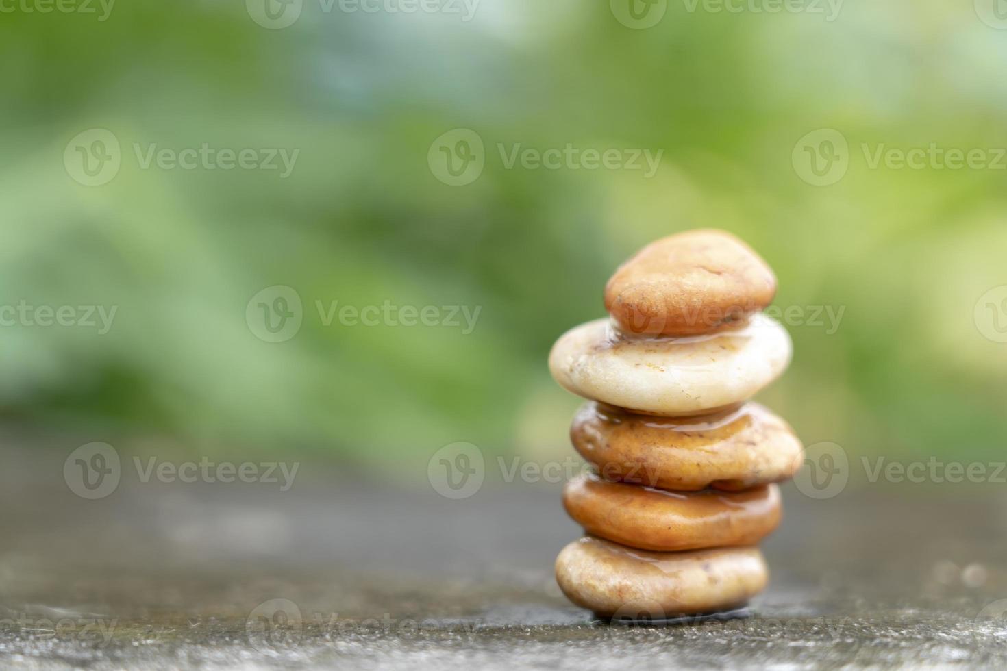 Meditation stones with rain drop water on cement floor on green nature background. Pyramid pebbles free space. Calm, buddhism symbol or aromatherapy set concept. photo