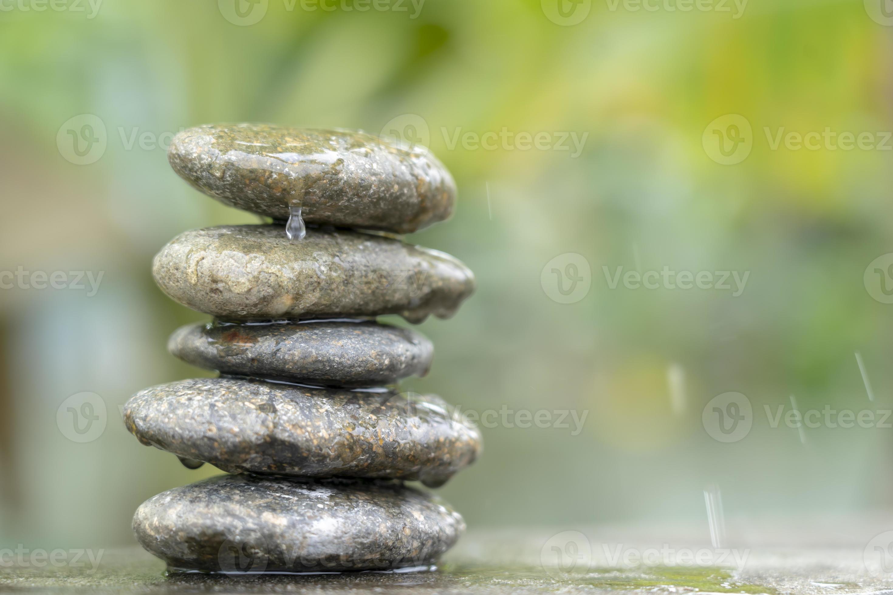 Meditation stones with rain drop water on cement floor on green